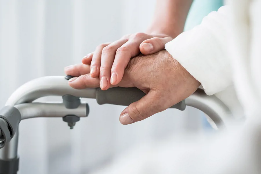 Sykepleier holder hånden over en pasients hånd. Omsorg.